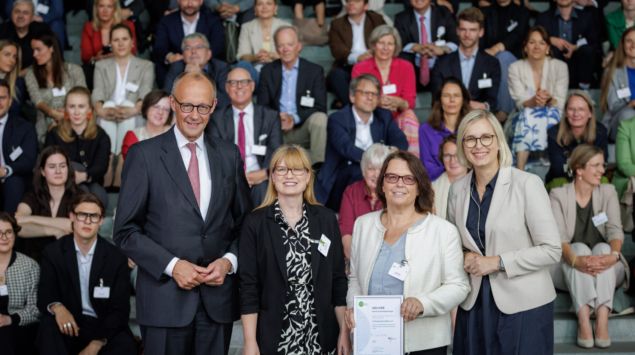 Bundeskanzler Friedrich Merz, Schirmherr von startsocial e.V., und Staatsministerin für Sport und Ehrenamt Dr. Christiane Schenderlein mit dem Bundespreisträger Irrsinnig Menschlich e.V., vertreten durch Caroline Lyle und Antje Wilde, auf der startsocial-Preisverleihung am 9. Juni 2026 in Berlin. Foto: Gordon Welters/startsocial e.V.