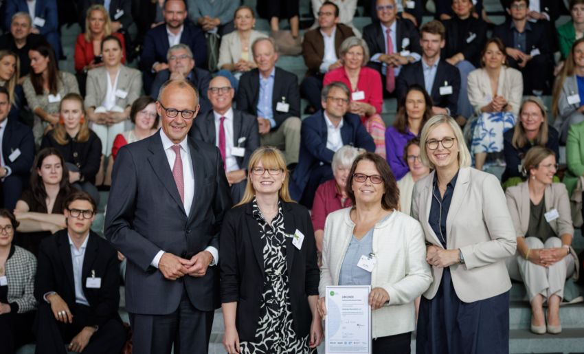 Bundeskanzler Friedrich Merz, Schirmherr von startsocial e.V., und Staatsministerin für Sport und Ehrenamt Dr. Christiane Schenderlein mit dem Bundespreisträger Irrsinnig Menschlich e.V., vertreten durch Caroline Lyle und Antje Wilde, auf der startsocial-Preisverleihung am 9. Juni 2026 in Berlin. Foto: Gordon Welters/startsocial e.V.