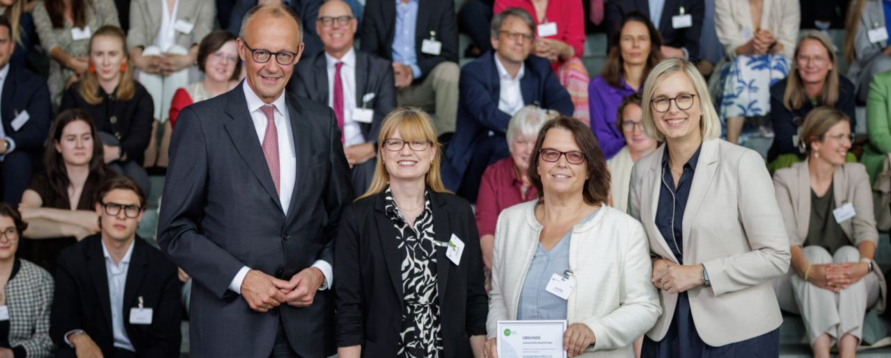 Bundeskanzler Friedrich Merz, Schirmherr von startsocial e.V., und Staatsministerin für Sport und Ehrenamt Dr. Christiane Schenderlein mit dem Bundespreisträger Irrsinnig Menschlich e.V., vertreten durch Caroline Lyle und Antje Wilde, auf der startsocial-Preisverleihung am 9. Juni 2026 in Berlin. Foto: Gordon Welters/startsocial e.V.